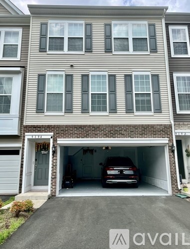 A two-story house with a garage and a car inside.