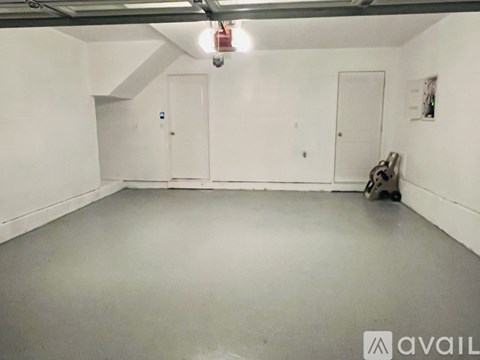 A spacious room with white walls and a grey floor.