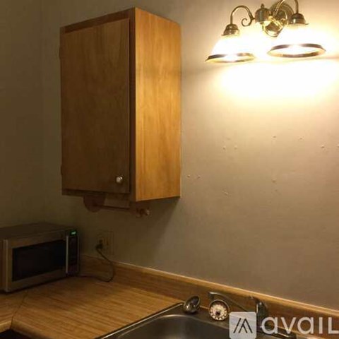A wooden cabinet is mounted on a wall above a microwave.