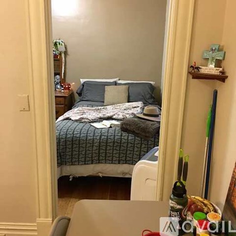 A bedroom with a bed, nightstand, and a table with items on it.