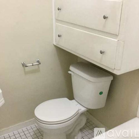 A white toilet with a white cabinet above it.