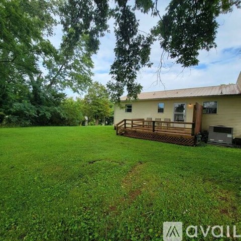 A house with a green lawn and trees in the background.