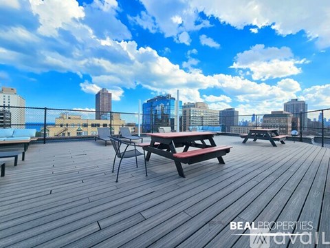 A wooden deck with picnic tables and chairs overlooking a city skyline.