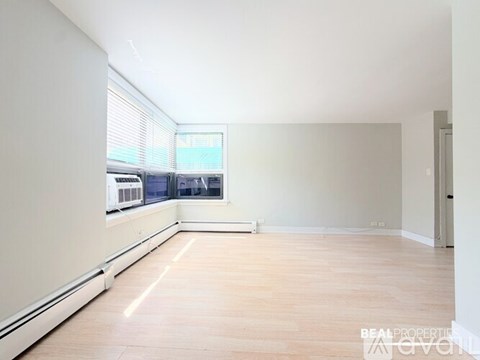A spacious room with wooden flooring and a large window.