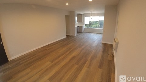 A spacious room with wooden flooring and a large window.
