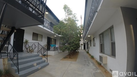 A white building with a black railing and a tree in front.