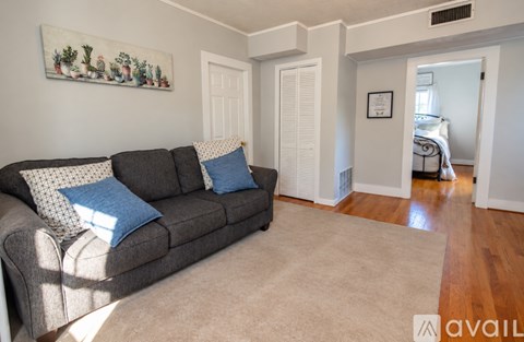A living room with a grey couch and a painting on the wall.