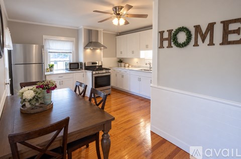 A kitchen with a dining table and chairs in front of a wall with the word HOME on it.