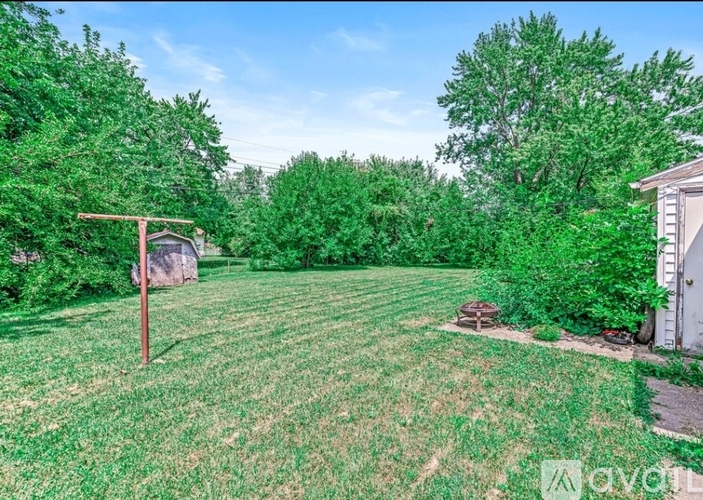 A backyard with a lawn, trees, and a small shed.