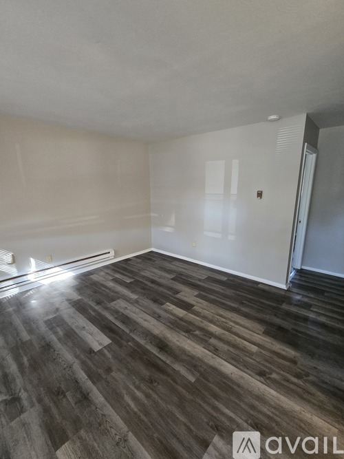 A room with wooden flooring and white walls.