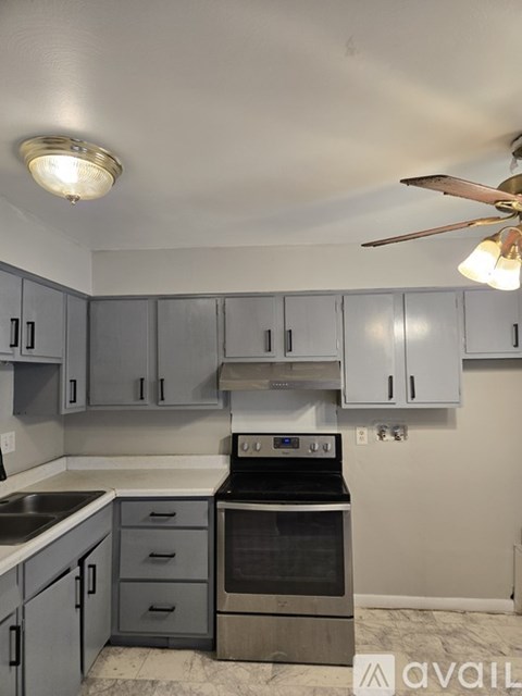 A kitchen with a stove top oven and a fan.