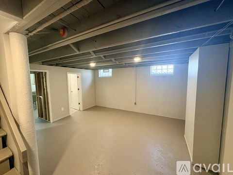 A spacious empty room with a staircase on the left side.