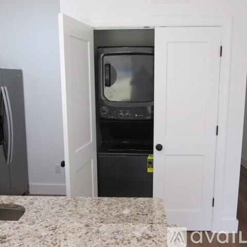 A small black oven is built into a white cabinet.