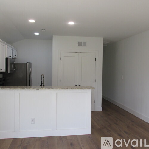 A kitchen with white cabinets and a black refrigerator.