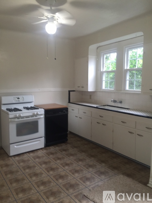A kitchen with a white stove and a fan on the ceiling.