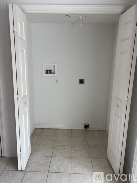 A white room with a picture on the wall and a small black square on the wall.