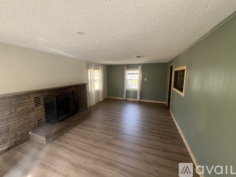 A living room with a fireplace and wood flooring.