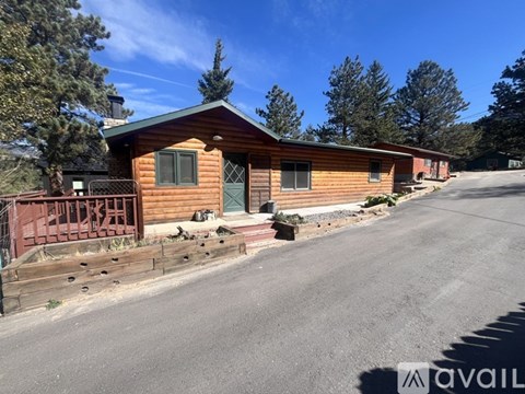 A wooden cabin with a green door is surrounded by a wooden fence.