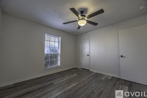 A room with a ceiling fan and wooden flooring.