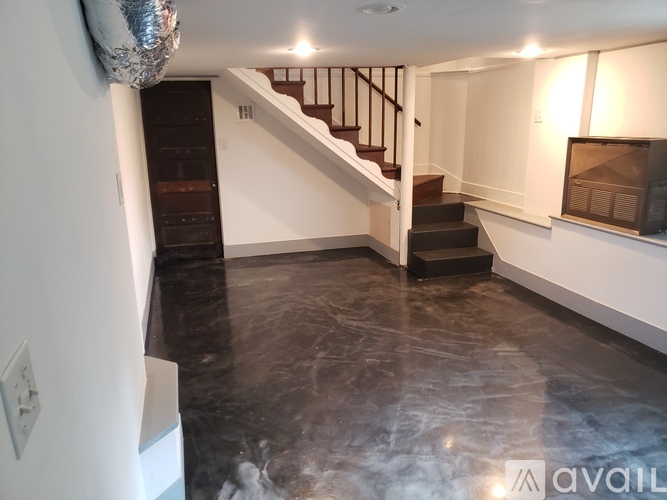 A spacious room with a staircase and a television.
