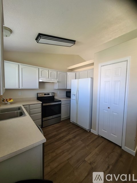 A kitchen with white cabinets and a wooden floor.
