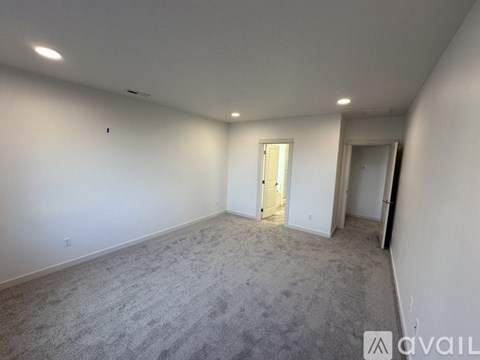 A spacious room with carpeted floor and white walls.