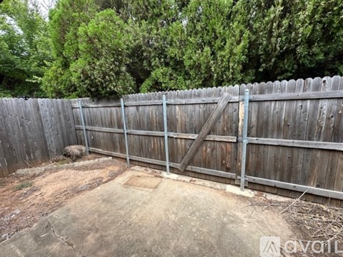 A wooden fence with a gate is in the foreground of a yard.