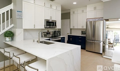 A kitchen with white cabinets and a marble countertop.