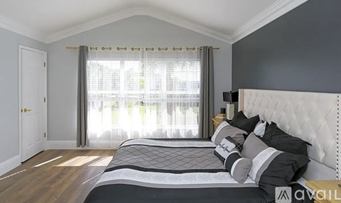 A bedroom with a large bed and a window with curtains.