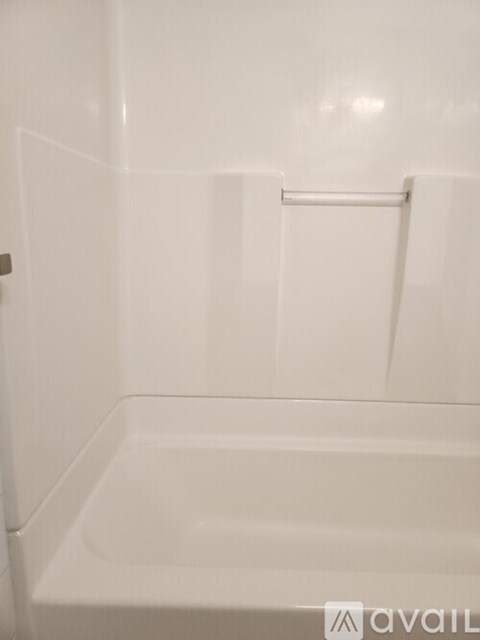 A white bathroom with a tub and a towel rack.