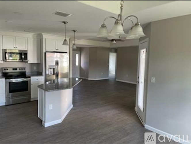 A modern kitchen with a stainless steel island and pendant lights.