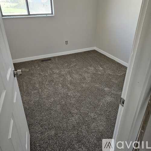A room with a carpeted floor and a window.
