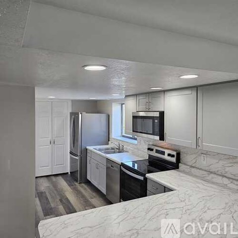 A kitchen with white cabinets and a marble countertop.