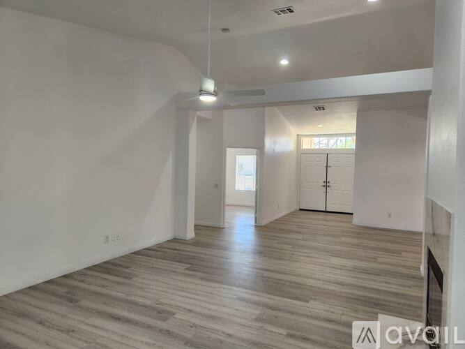 A spacious room with wooden flooring and white walls.