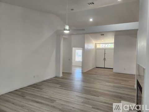 A spacious room with wooden flooring and white walls.