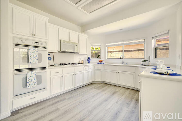 A kitchen with white cabinets and a wooden floor.