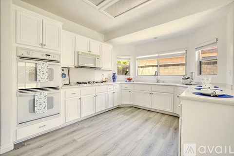 A kitchen with white cabinets and a wooden floor.