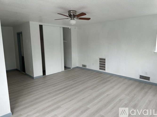 A room with a ceiling fan and wooden flooring.