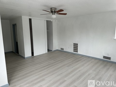 A room with a ceiling fan and wooden flooring.
