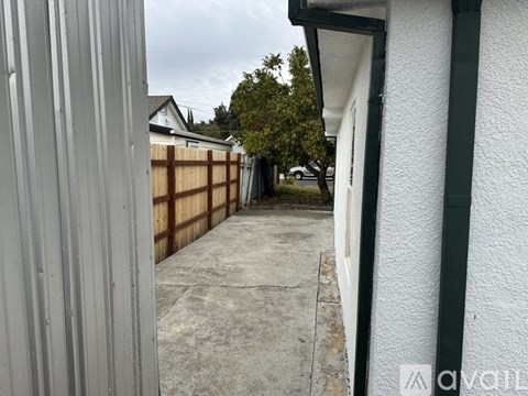 A white house with a grey wall and a concrete floor.