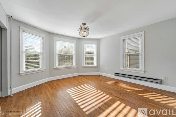 A sunlit room with hardwood floors and white walls.