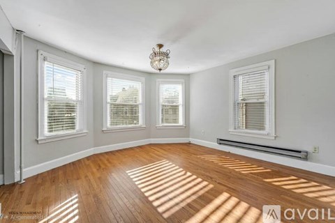 A sunlit room with hardwood floors and white walls.