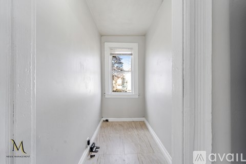 A long hallway with a window and a door on the left.