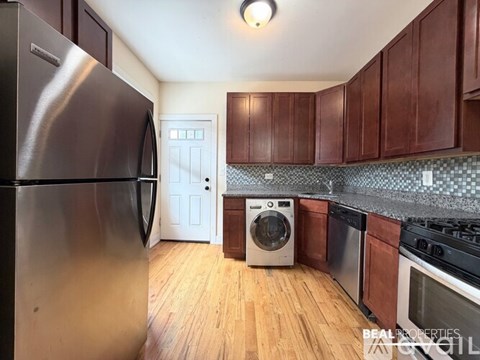 A kitchen with a stainless steel refrigerator and wooden cabinets.