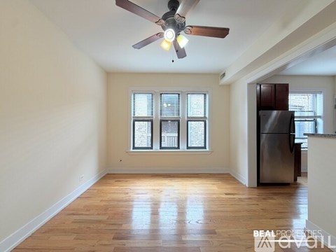 A spacious room with a ceiling fan and wooden flooring.
