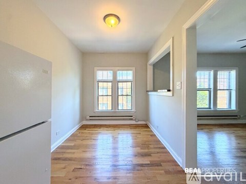 A spacious room with wooden floors and a large window.