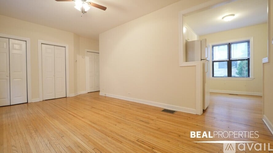 A room with wooden flooring and a window with a view of trees.