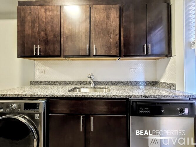 A kitchen with dark brown cabinets and a granite countertop.
