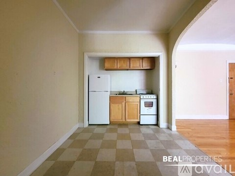 A kitchen with a white fridge and a white oven with a wooden cabinet above it.