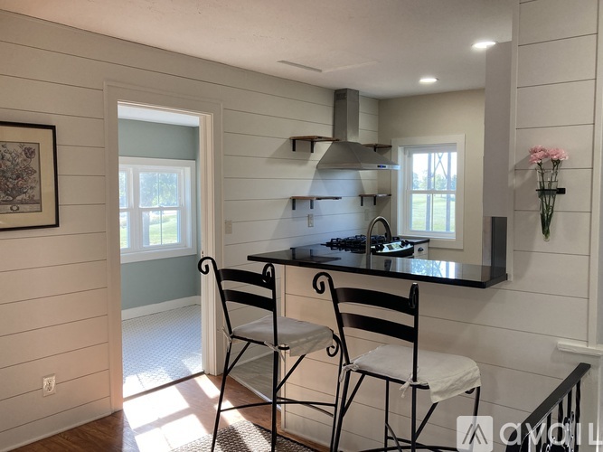 A kitchen with a black counter top and two chairs.